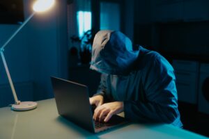 Cybersecurity Scene Hooded Man Focused on Laptop at Home Kitchen